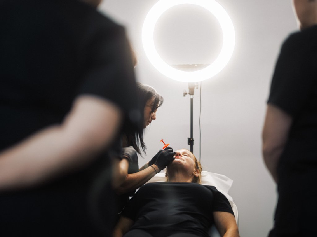 A student at the Aesthetic Training Academy learning how to safely inject dermal filler to a patient's face.