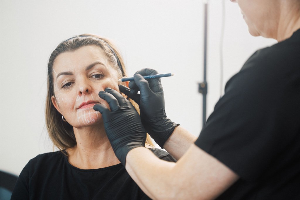 Dr Lauren teaching her students at the ATA proper medical aesthetic techniques, using facial mapping on a live model to illustrate facial muscle anatomy.