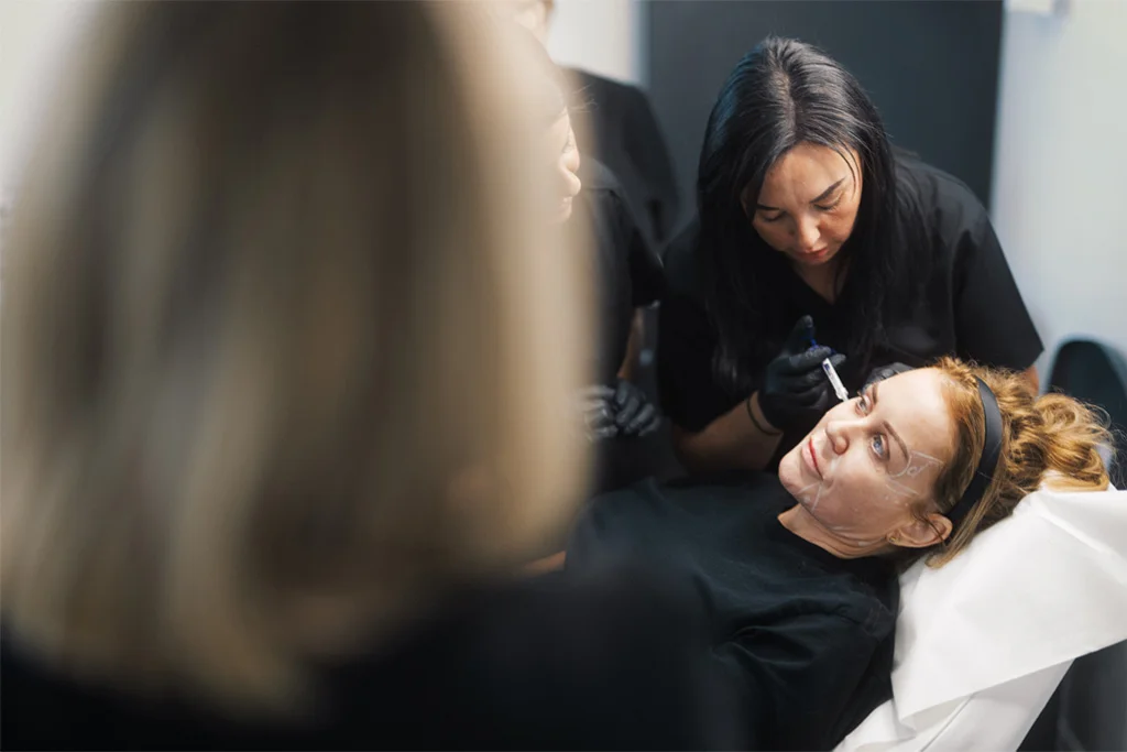 A student injecting dermal fillers to a model patient at the ATA.